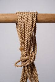 Natural Lovey Subby jute rope looped and hanging on a white background.