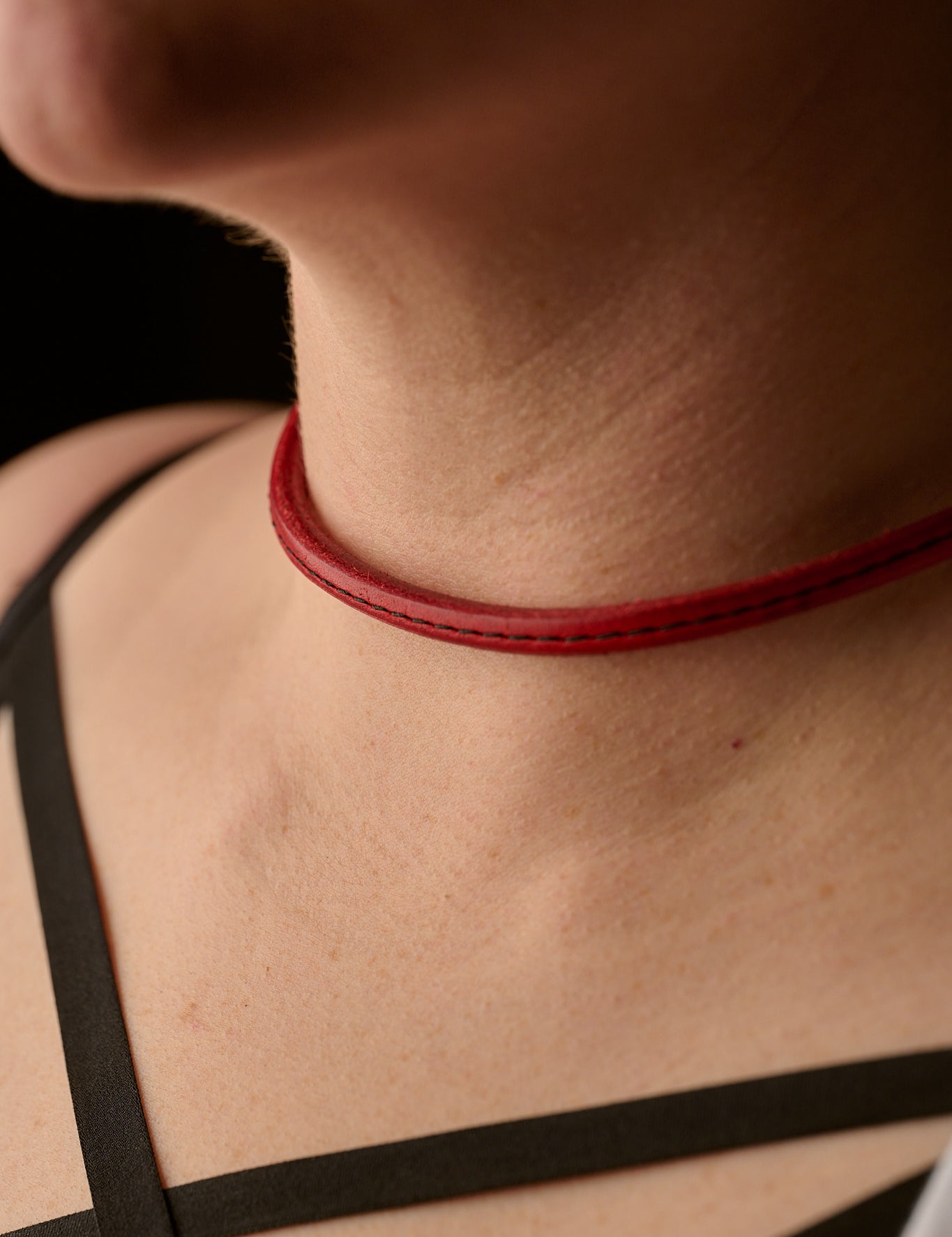 Close-up of a person wearing a red choker necklace with a blurred background