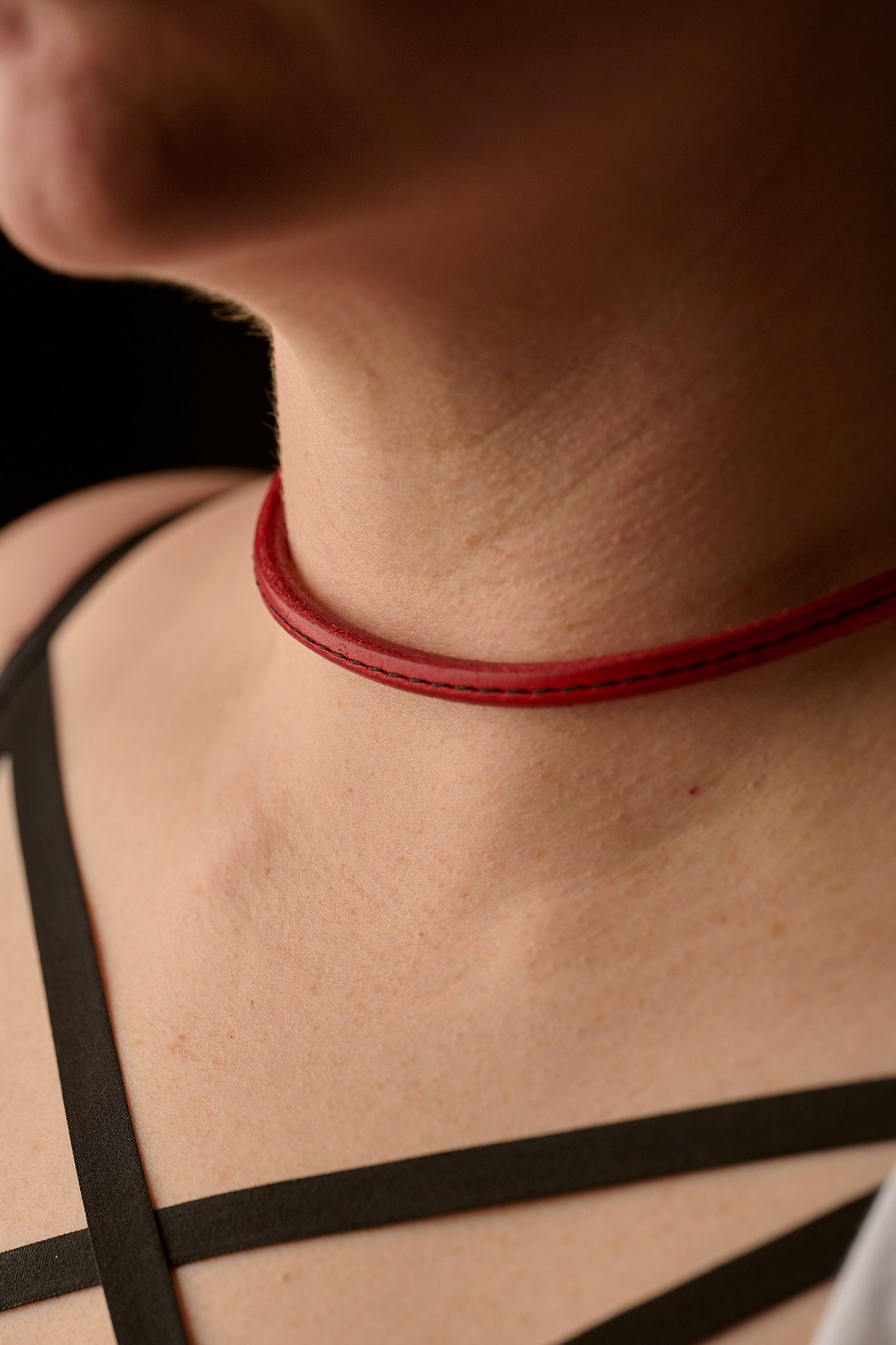 Close-up of a person wearing a red choker necklace with a blurred background