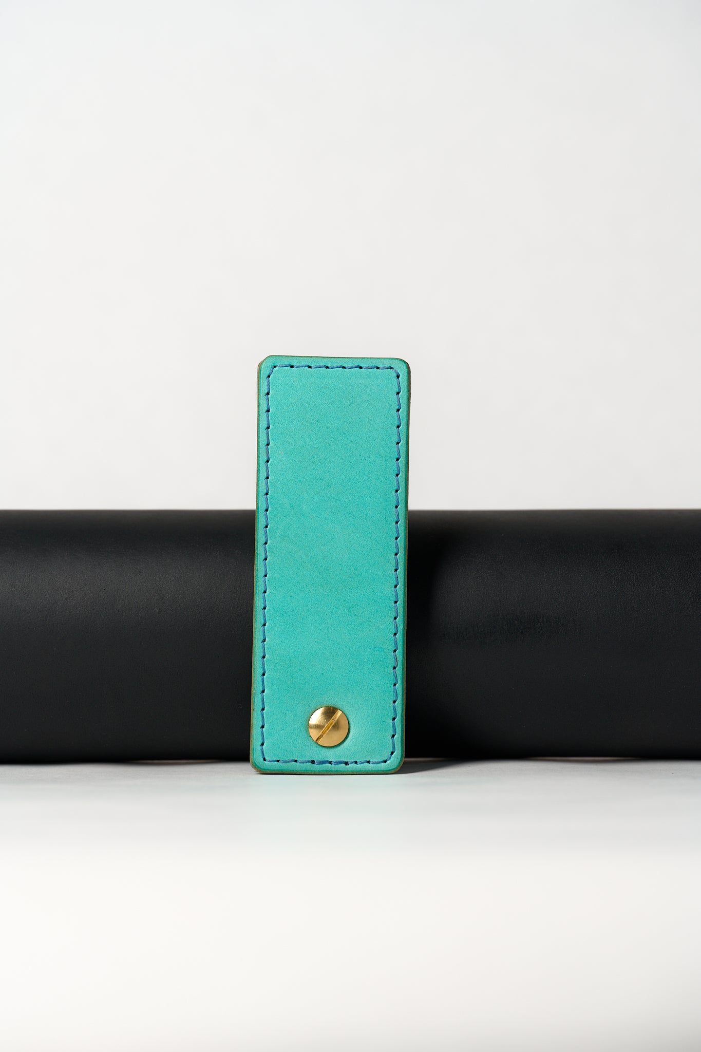 foldable blue leather travel size belt with rivets on white background.